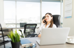 women at her desk talking on the phone looking away from computer