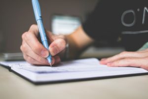 Men writing information in notebook