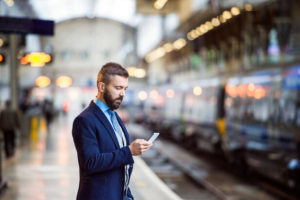 Businessman on his phone waiting for train