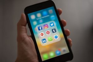 Close up of men hands while holding phone that shows the social media apps